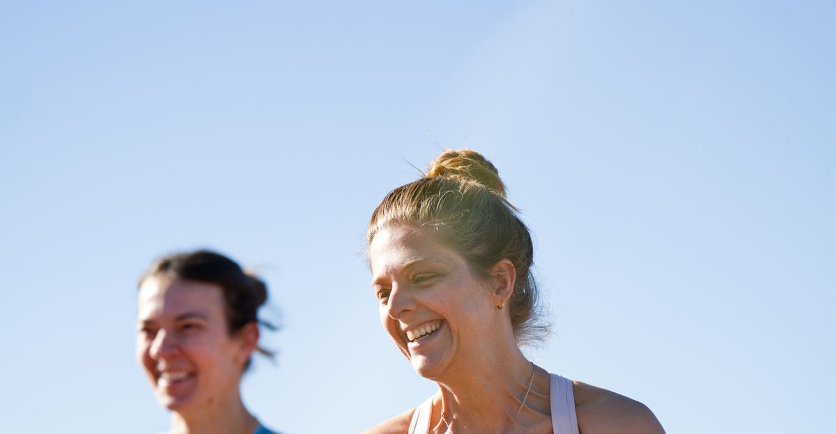 Two women running under a clear blue sky